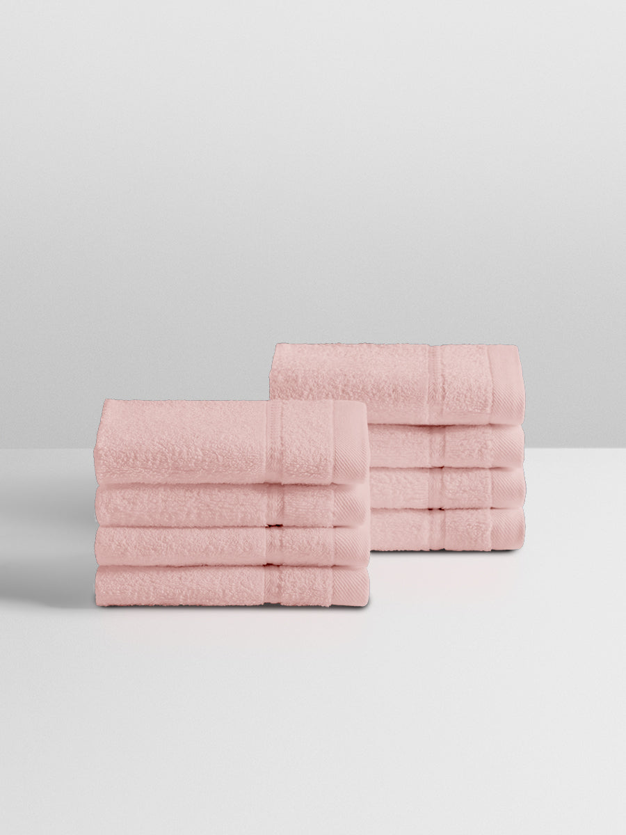 A stack of eight soft, “Kyoto Blush” colored clothes neatly folded on a white surface.