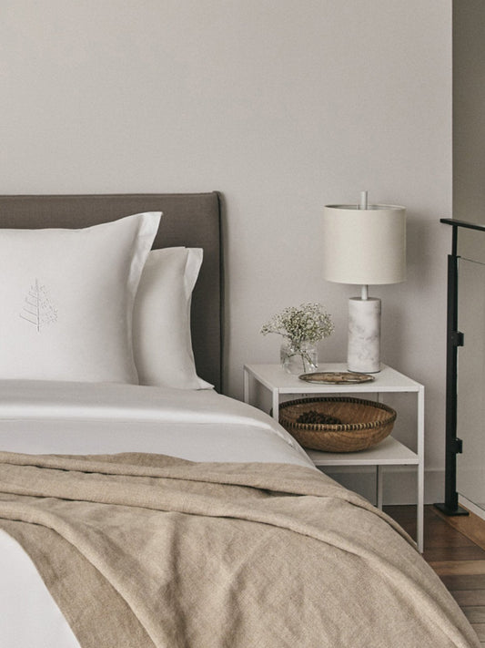 A beautifully made bed showcasing a crisp white duvet and a cozy throw blanket.