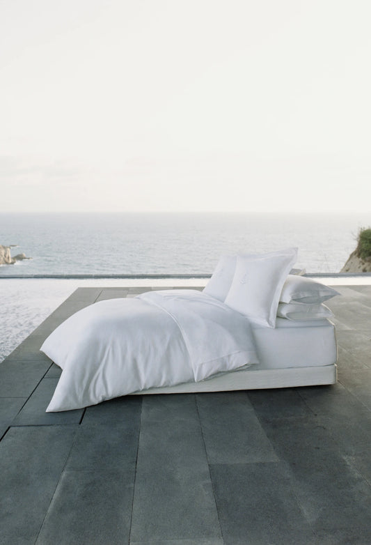 White bedding set on a bed with a scenic background