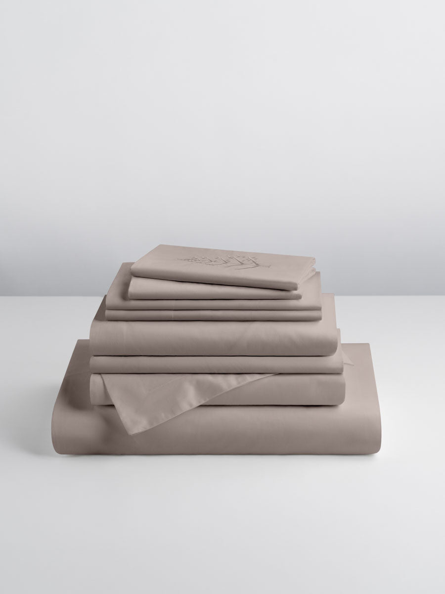 A set of Moroccan Sand-colored sheets, folded into perfect rectangles and stacked on a flat surface.