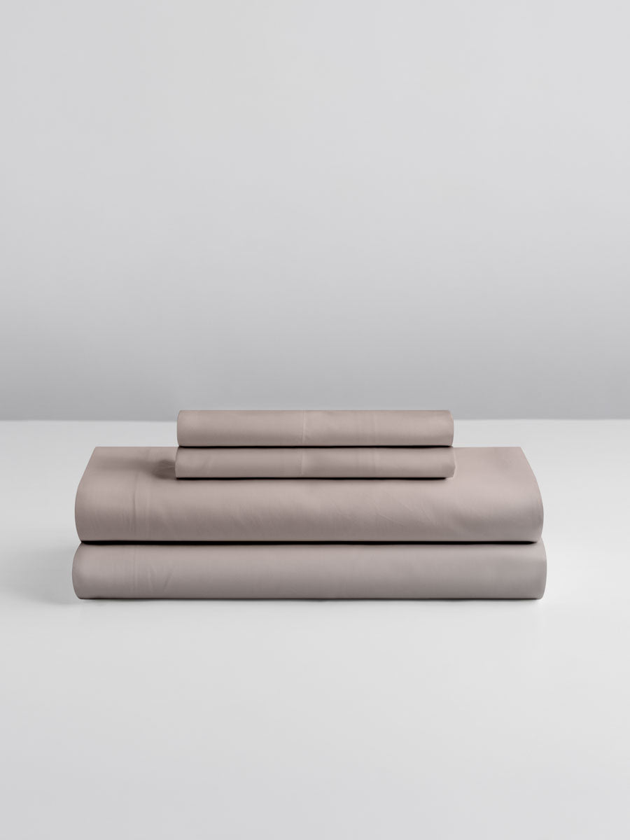 A set of Moroccan Sand-colored sheets, folded into perfect rectangles and stacked on a flat surface.