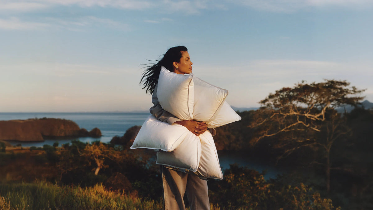 Guest holding Four Seasons pillows overlooking the ocean