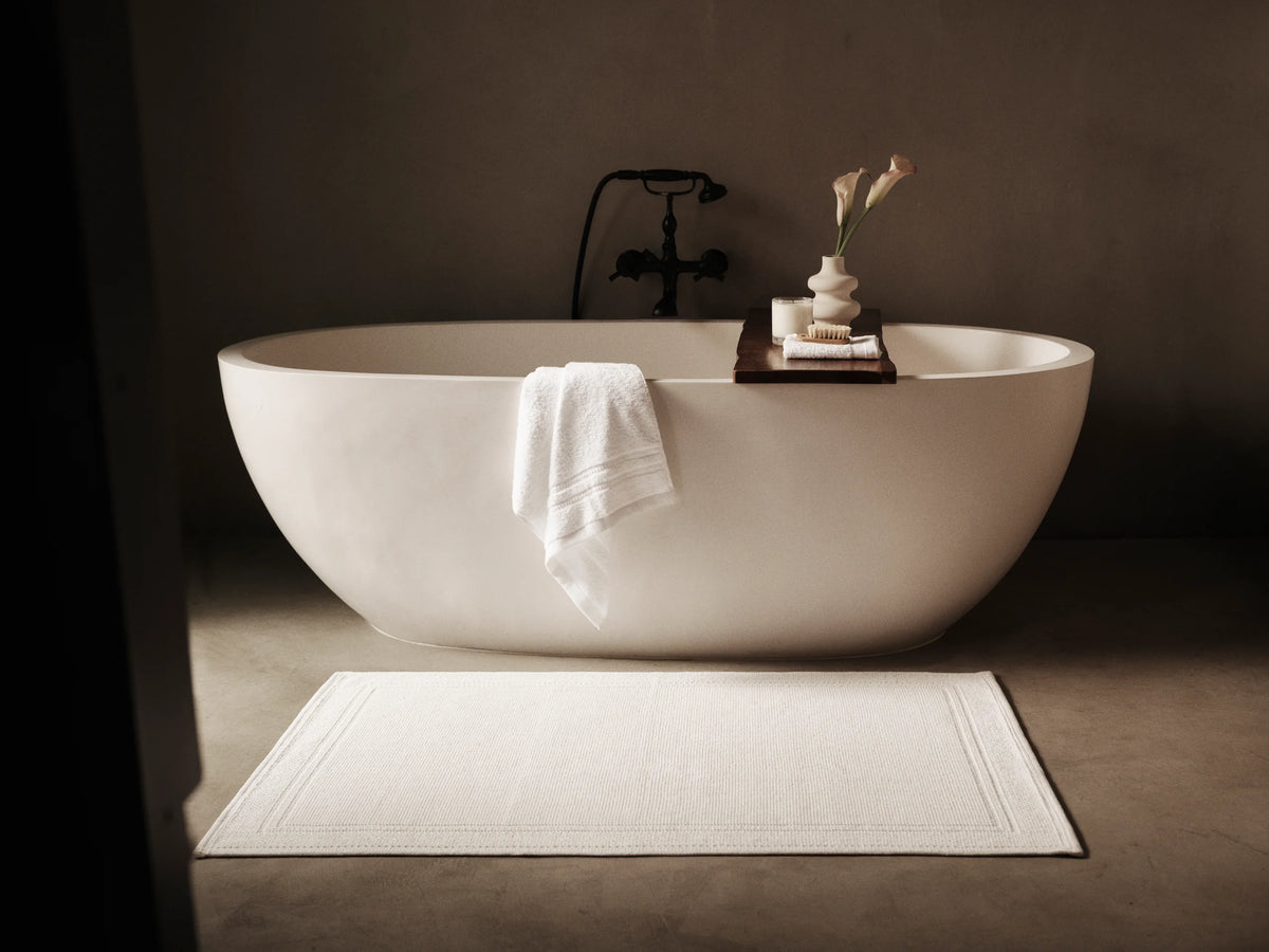 Four Seasons white bath mat beside a freestanding bathtub