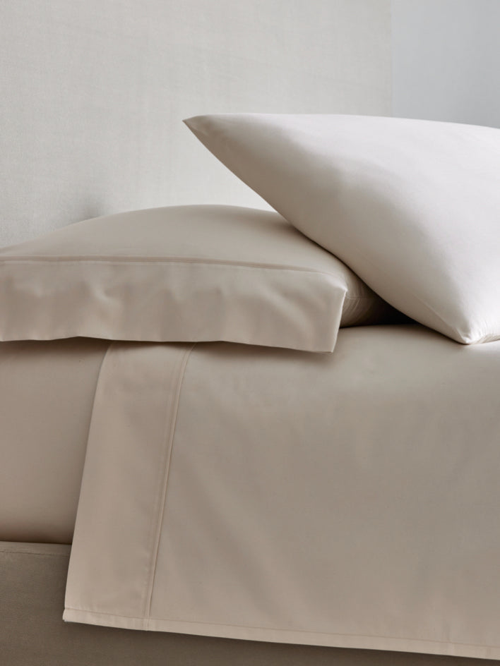 A bed with sheets and two pillows in Signature White/Balinese Pearl color. - {{Signature White/Balinese Pearl}}