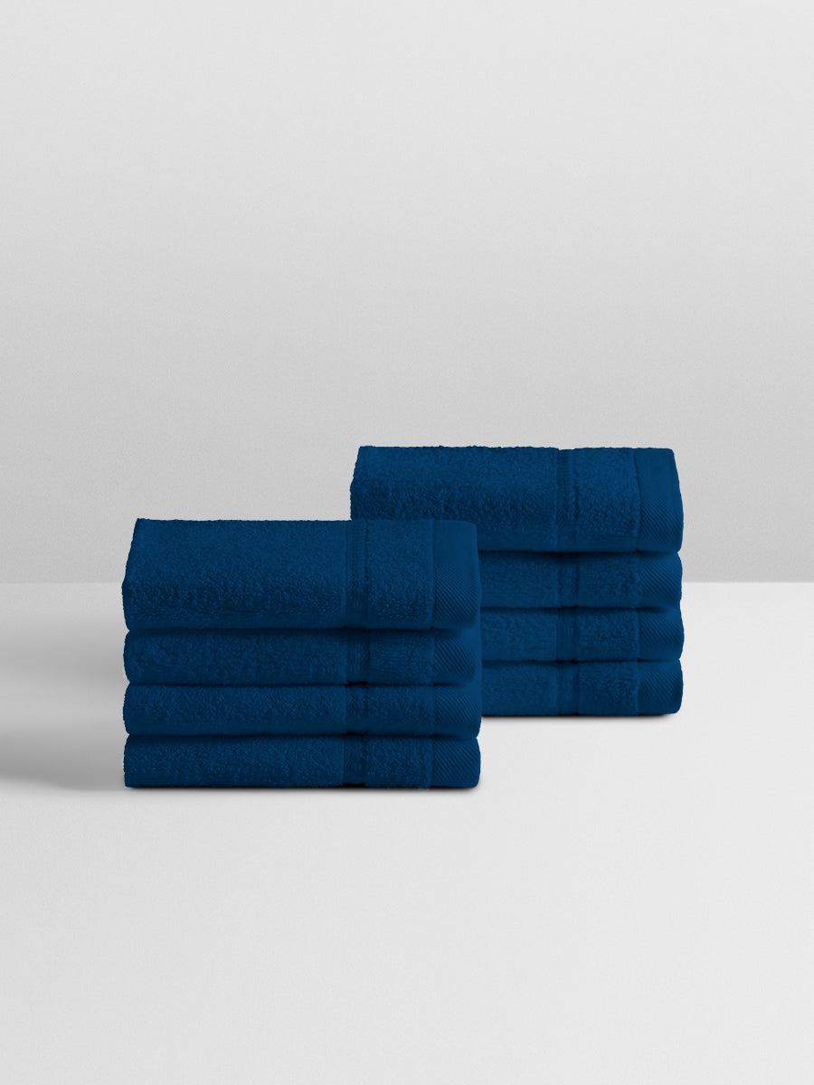 A stack of eight soft, “Riviera Navy” colored bath wash cloth neatly folded on a white surface.