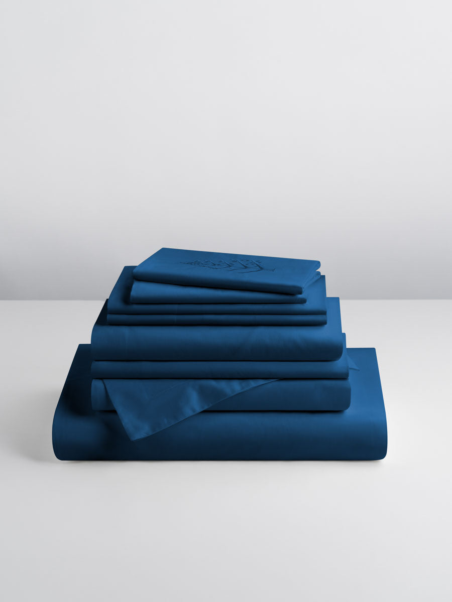 A set of Rivera Navy-colored sheets, folded into perfect rectangles and stacked on a flat surface.