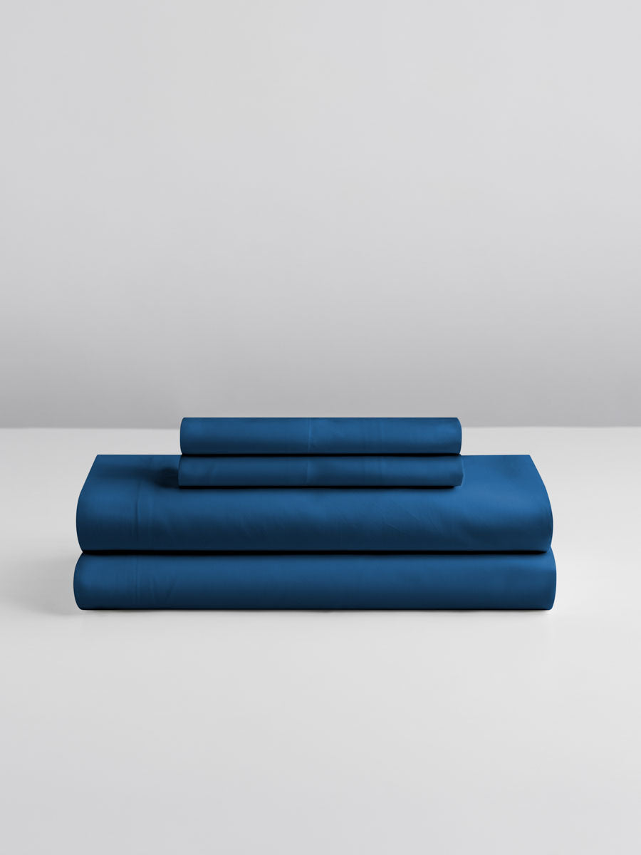 A set of Rivera Navy-colored sheets, folded into perfect rectangles and stacked on a flat surface.