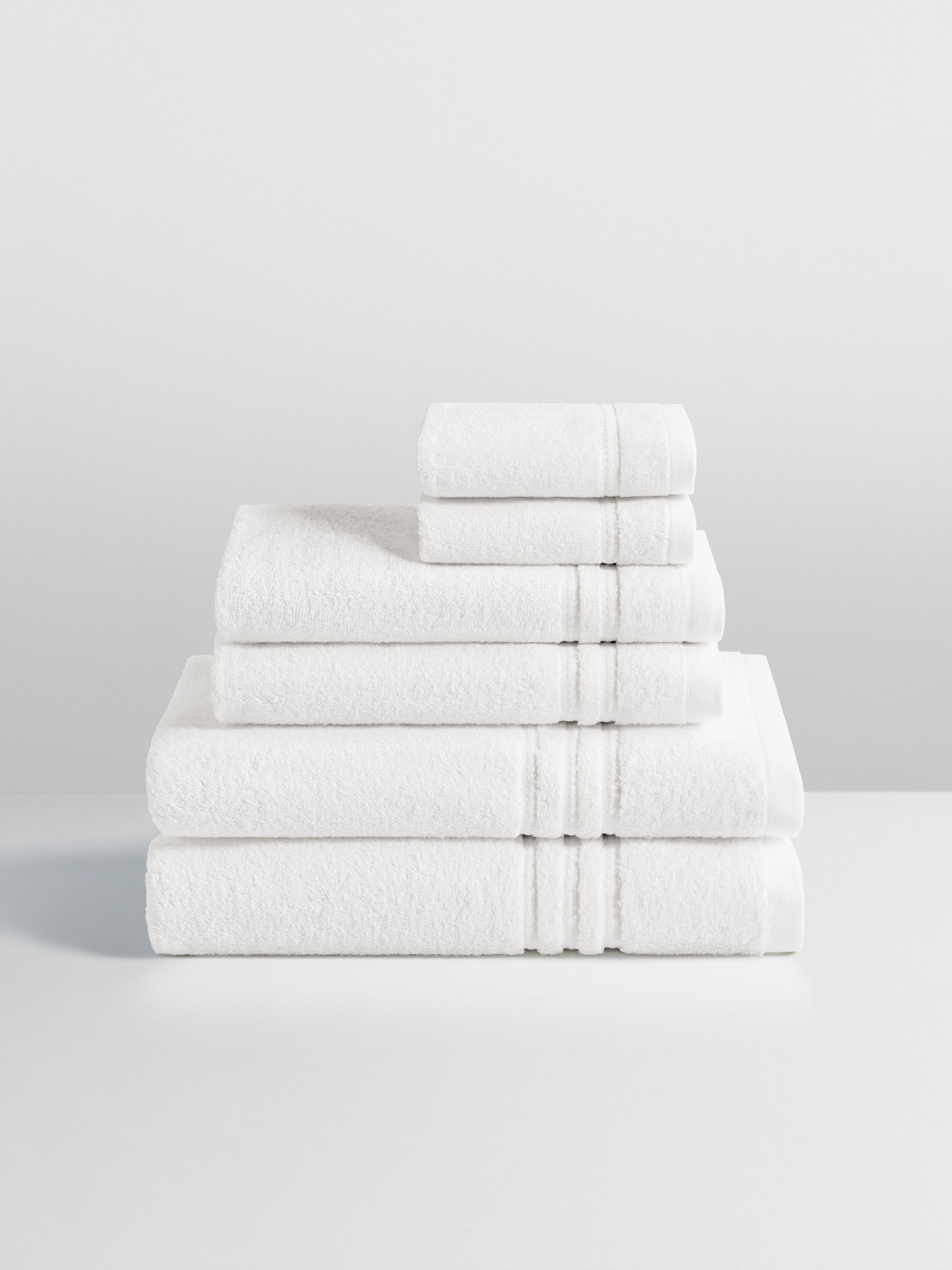 6-piece colored towel set in Signature White, finished with a patterned dobby border. - {{Signature White}}