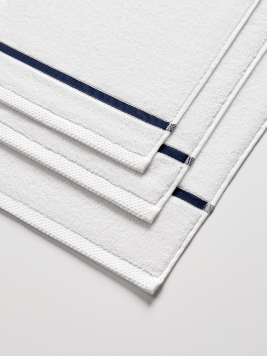 Sycamore Bath Towel Set in Signature White—close-up of stacked towels showing the navy piping detail. - {{Signature White}}