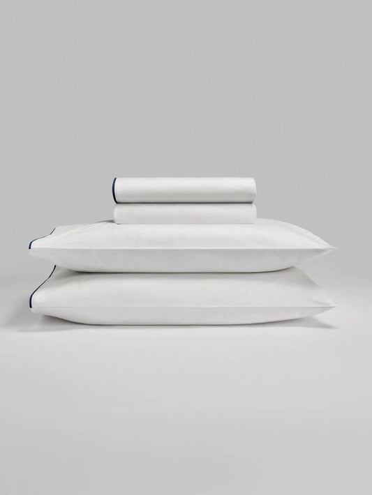 Sycamore Sheet Set in Signature White — folded fitted and flat sheets stacked over matching pillowcases. - {{Signature White}}