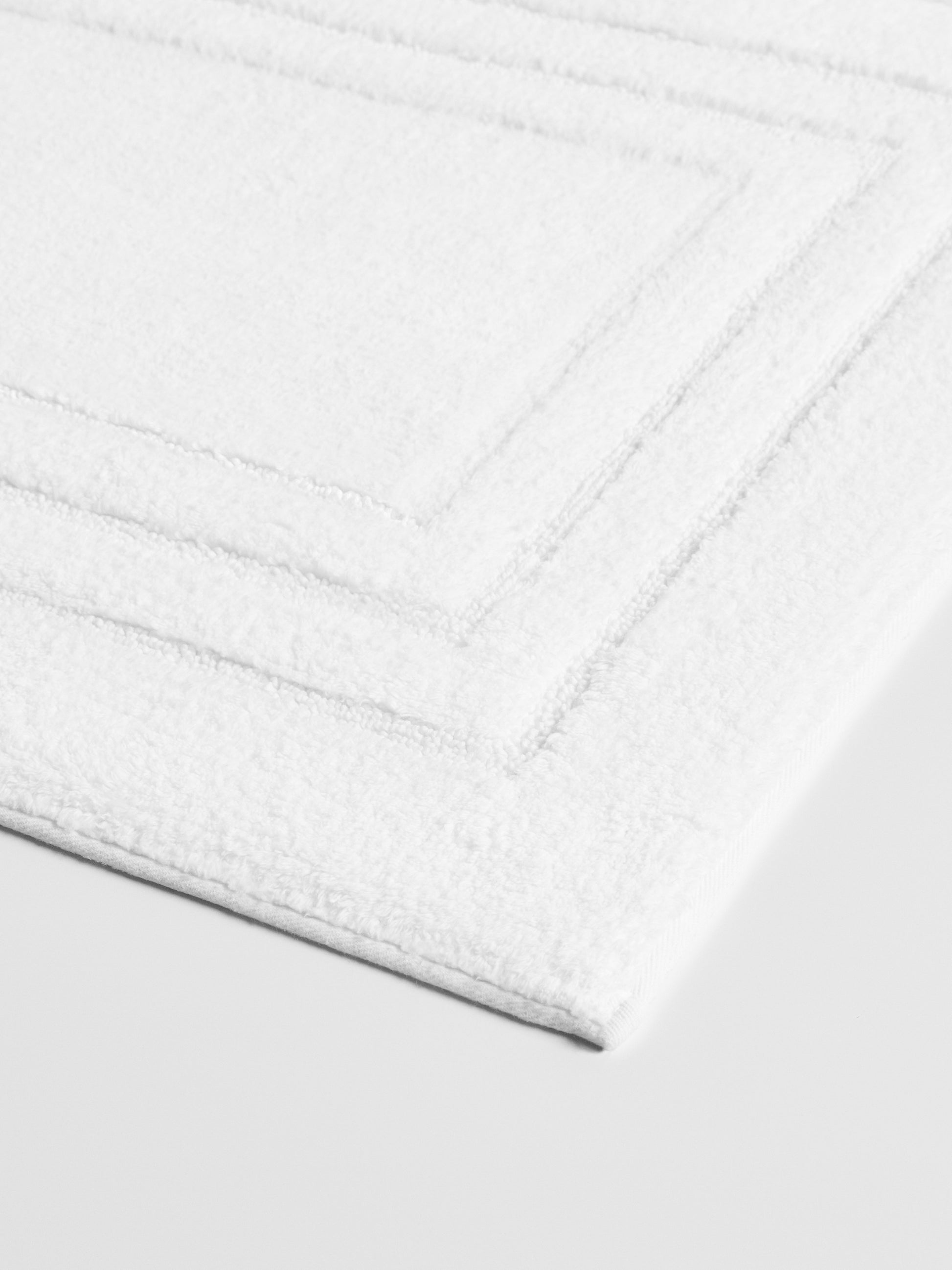 Luxurious white bath mat with a triple frame design and a plush, soft texture.