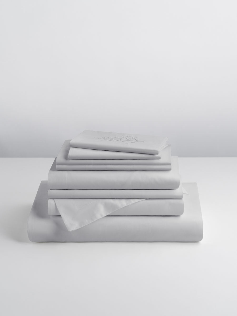 A set of Turkish Silver-colored sheets, folded into perfect rectangles and stacked on a flat surface.