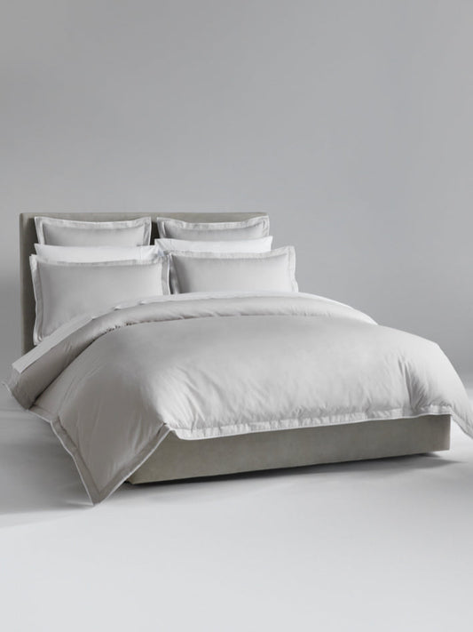 The bed is dressed with Signature White bedding and has several pillows arranged at the headboard. - {{Signature White}}