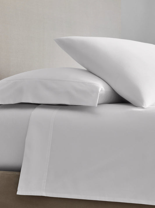 A bed with sheets and two pillows in Signature White color. - {{Signature White}}