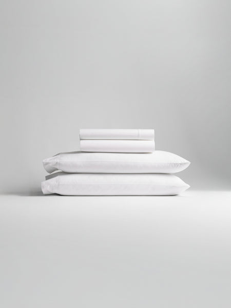 A stack of bedding, including pillowcases and sheets in Signature White color.