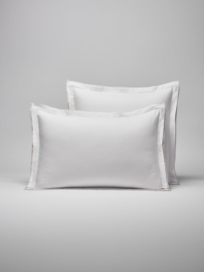 Two pillows with a woven border around them, one placed behind the other. - {{Signature White/Balinese Pearl}}