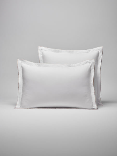 Two pillows with a woven border around them, one placed behind the other.