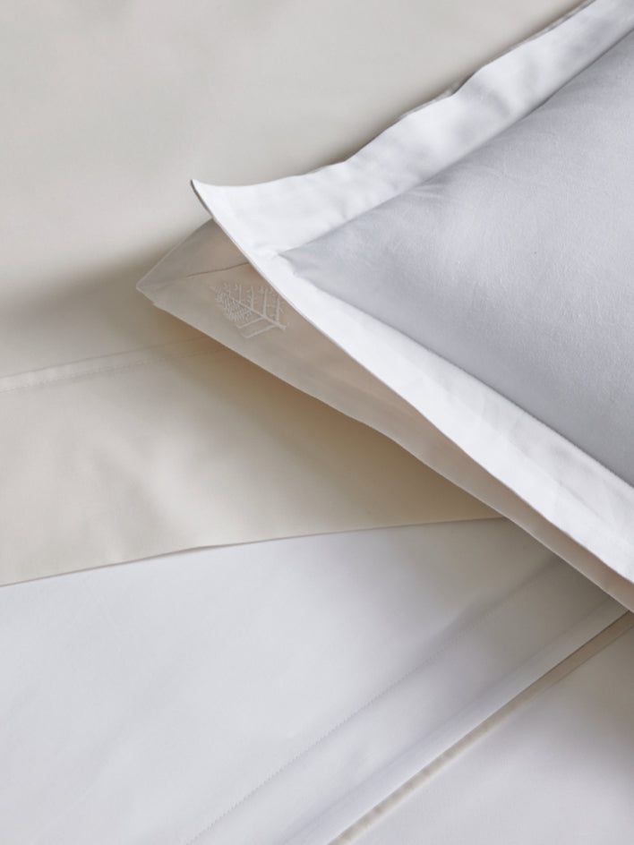 Close-up of a white pillowcase with a subtle pattern of the Four Seasons logo. The fabric is soft and luxurious.