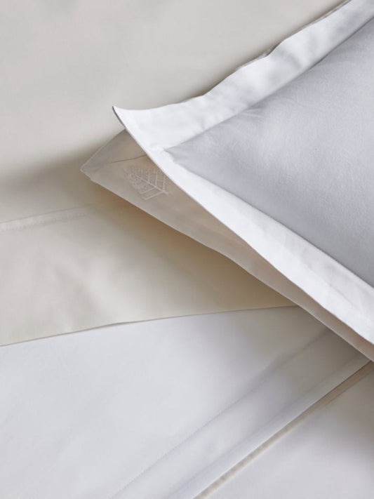 Close-up of a white pillowcase with a subtle pattern of the Four Seasons logo. The fabric is soft and luxurious. - {{Signature White/Balinese Pearl}}
