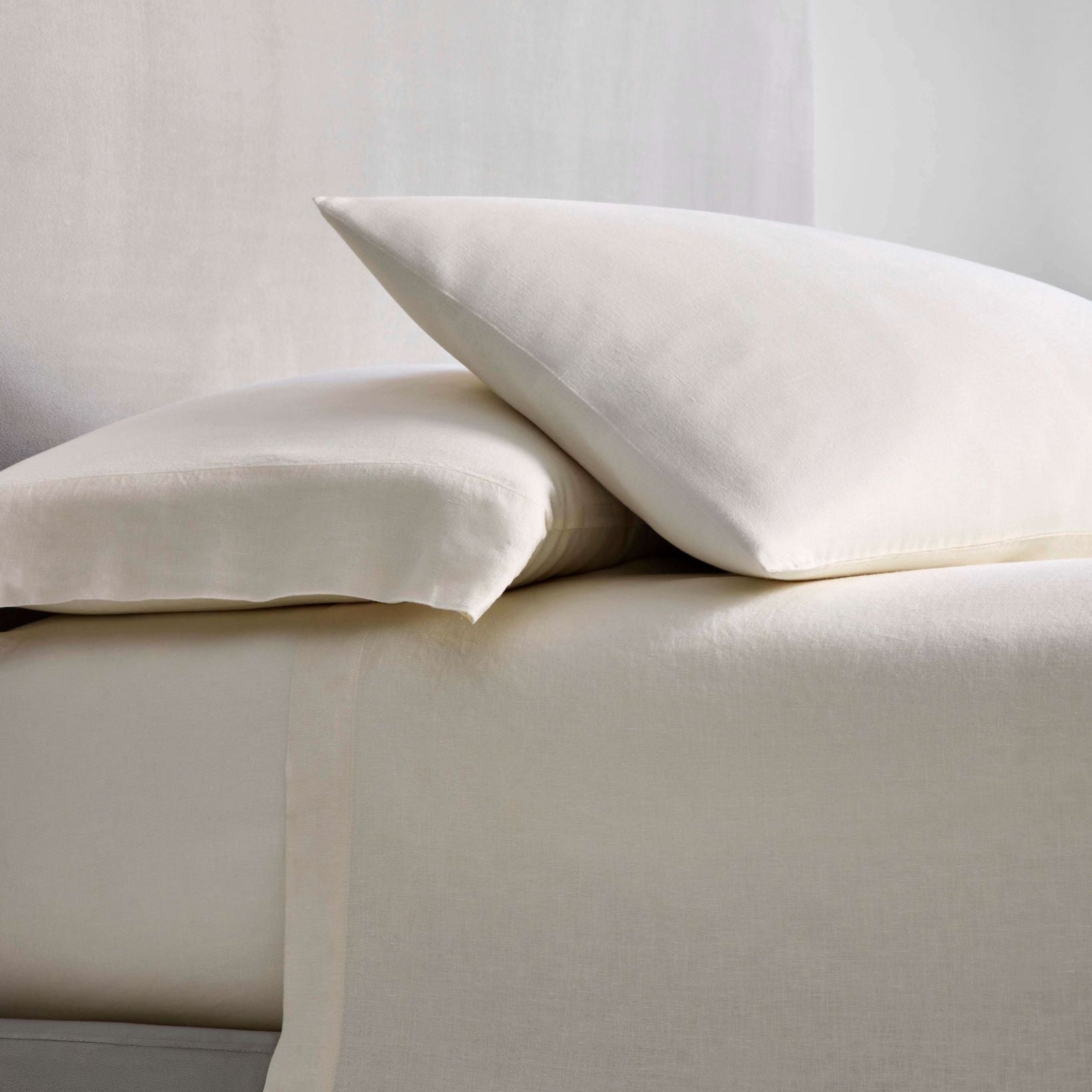 Acacia Sheet Set in Balinese Pearl — stacked pillowcases and flat sheet, linen fabric detail at the bedside. - {{Balinese Pearl}}