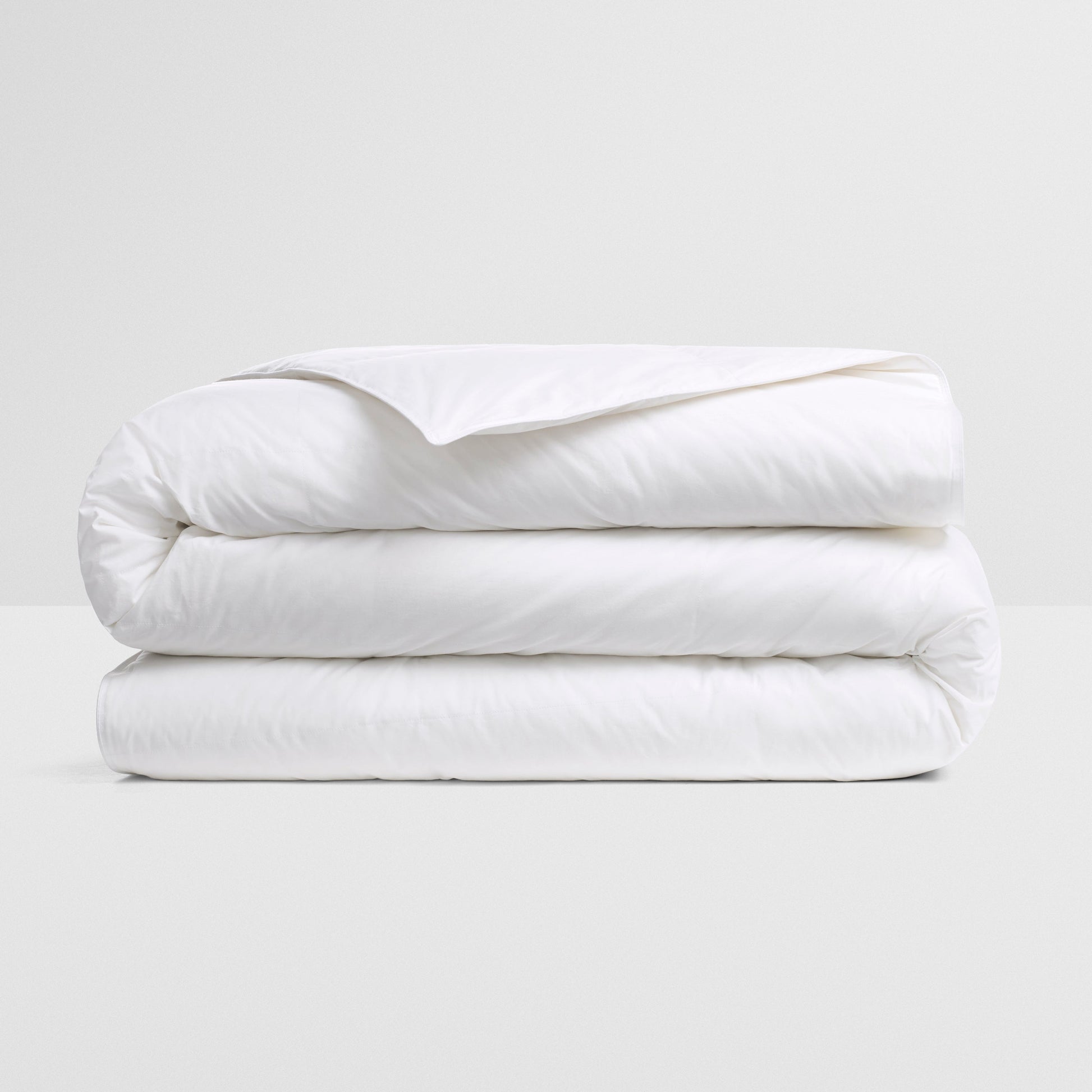 All Seasons Duvet — premium white down insert, neatly folded on a neutral surface for year-round comfort.