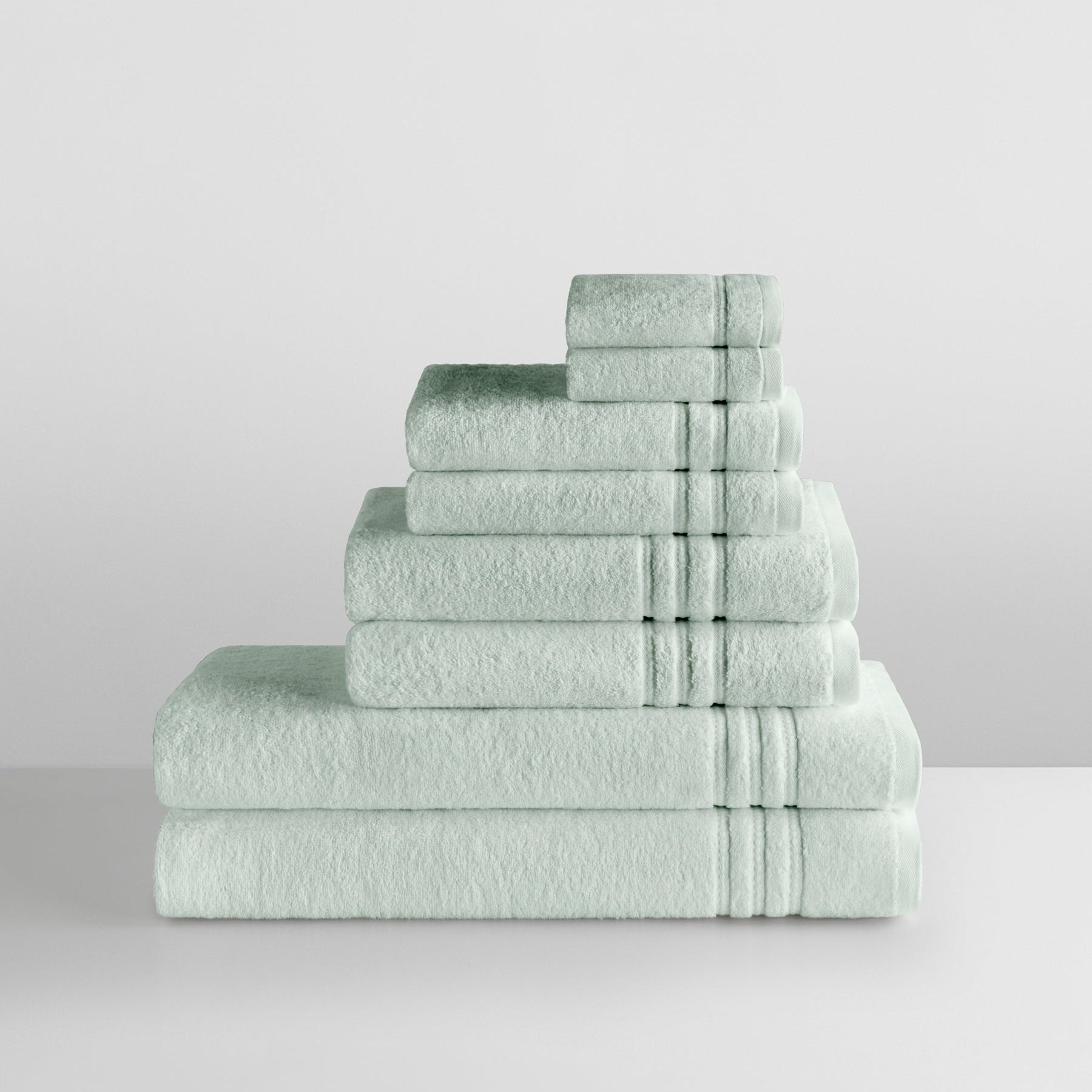 Stack of Florentine Sage towels in graduated sizes with dobby borders, arranged on a white surface. - {{Florentine Sage}}
