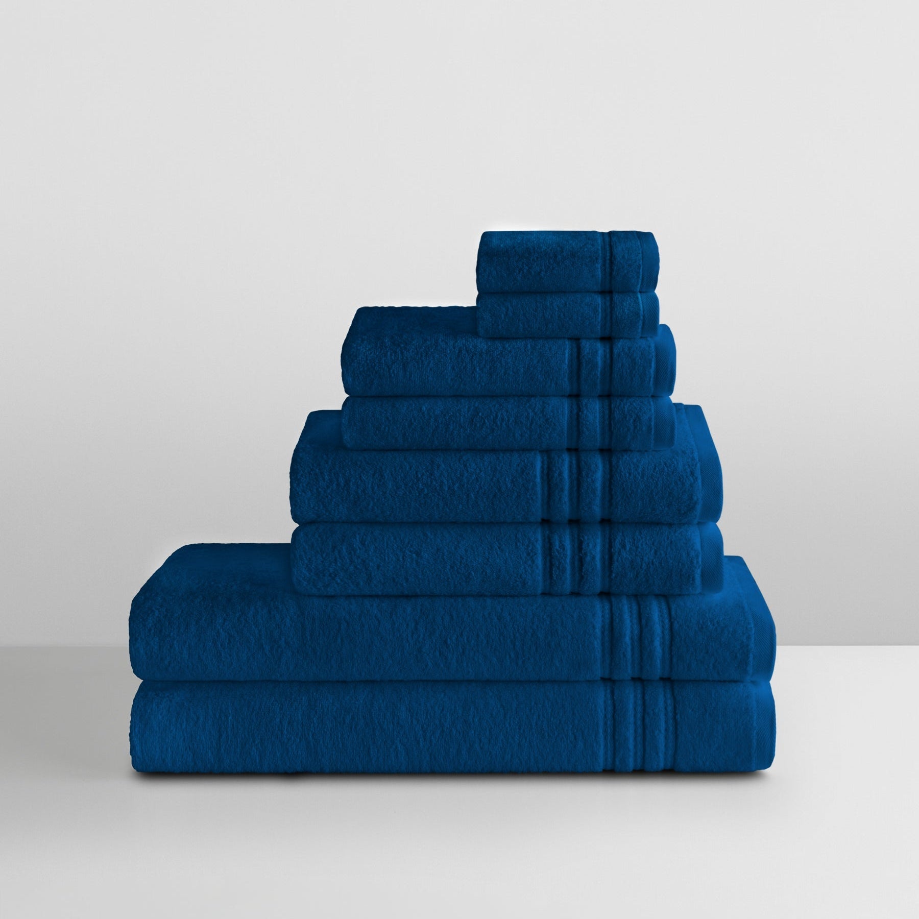 Stack of Riviera Navy towels in graduated sizes with dobby borders, neatly folded on a white surface. - {{Riviera Navy}}