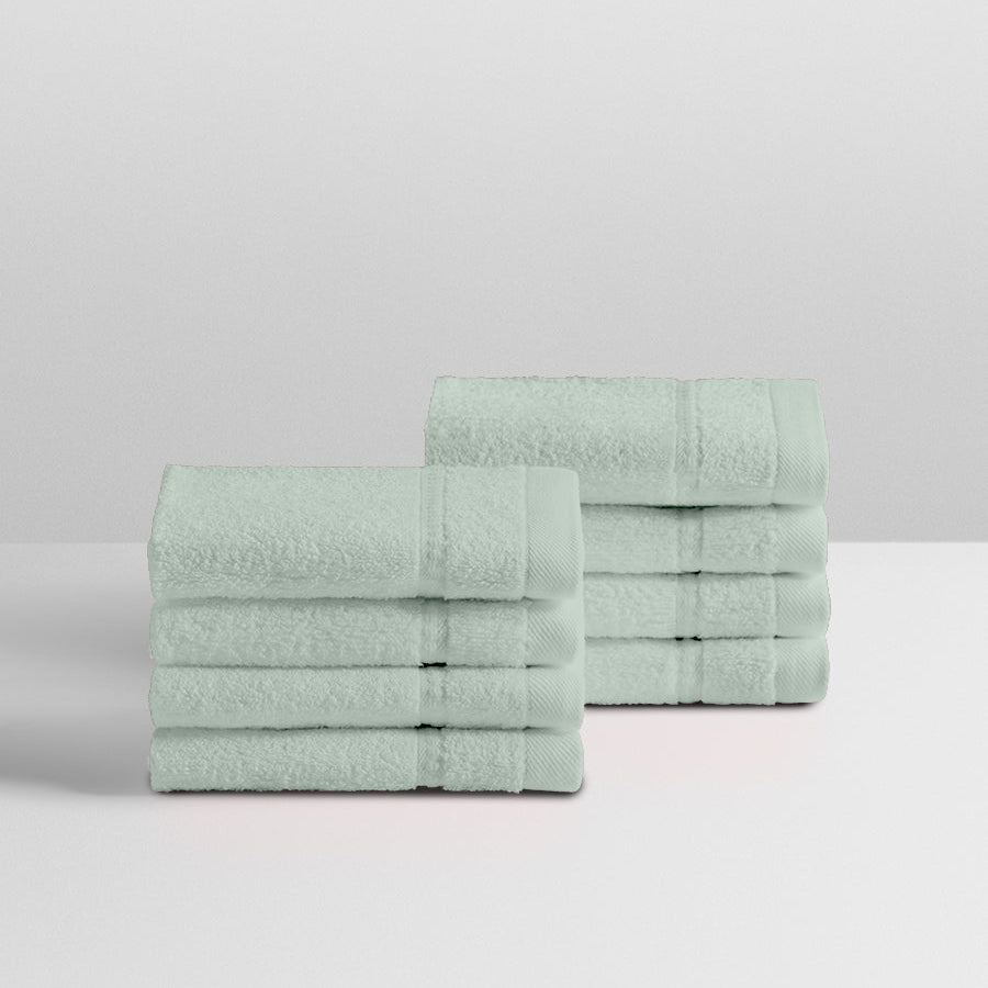 A stack of eight soft, “Florentine Sage” colored clothes neatly folded on a white surface. - {{Florentine Sage}}