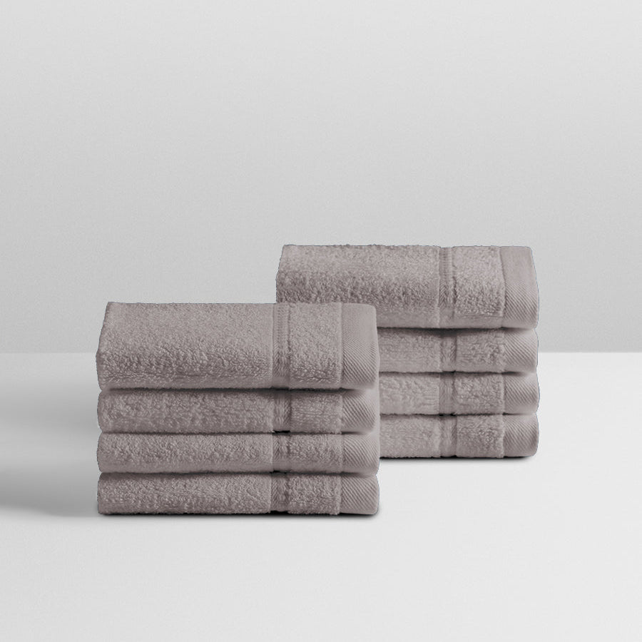 A stack of eight soft, “Hampshire Charcoal” colored bath wash clothes neatly folded on a white surface. - {{Hampshire Charcoal}}