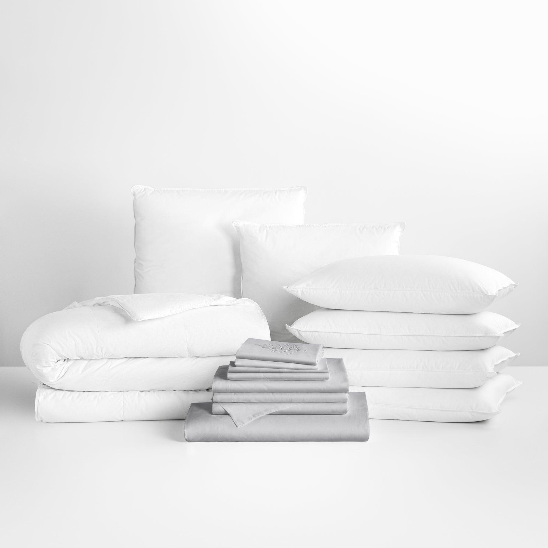 Turkish Silver-colored sheet set in the foreground, with stacked pillows and a neatly folded duvet in the background. - {{Turkish Silver}}
