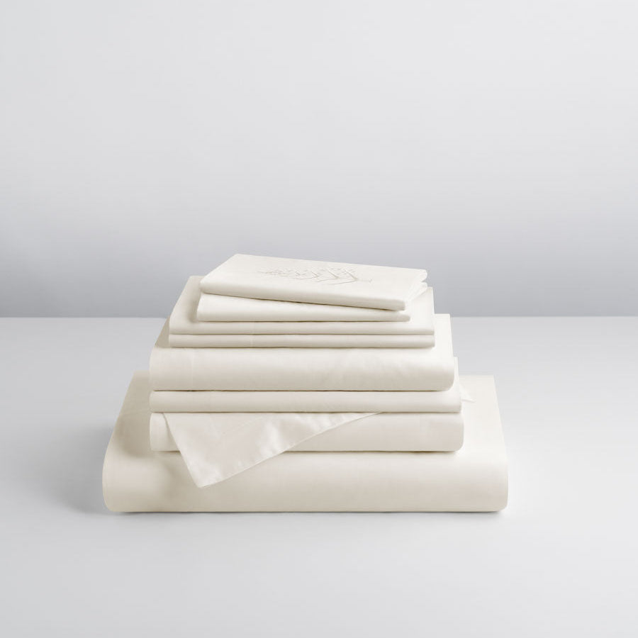 Stacked Signature Hotel Linen Set in Balinese Pearl — folded duvet cover, flat and fitted sheets, and pillowcases topped with an embroidered store logo. {{Balinese Pearl}}