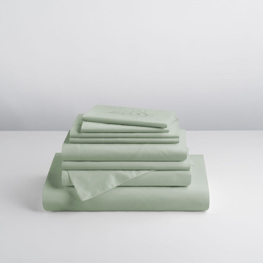 Stacked Florentine Sage linen set folded neatly on a white surface, featuring the store logo on top piece. {{Florentine Sage}}
