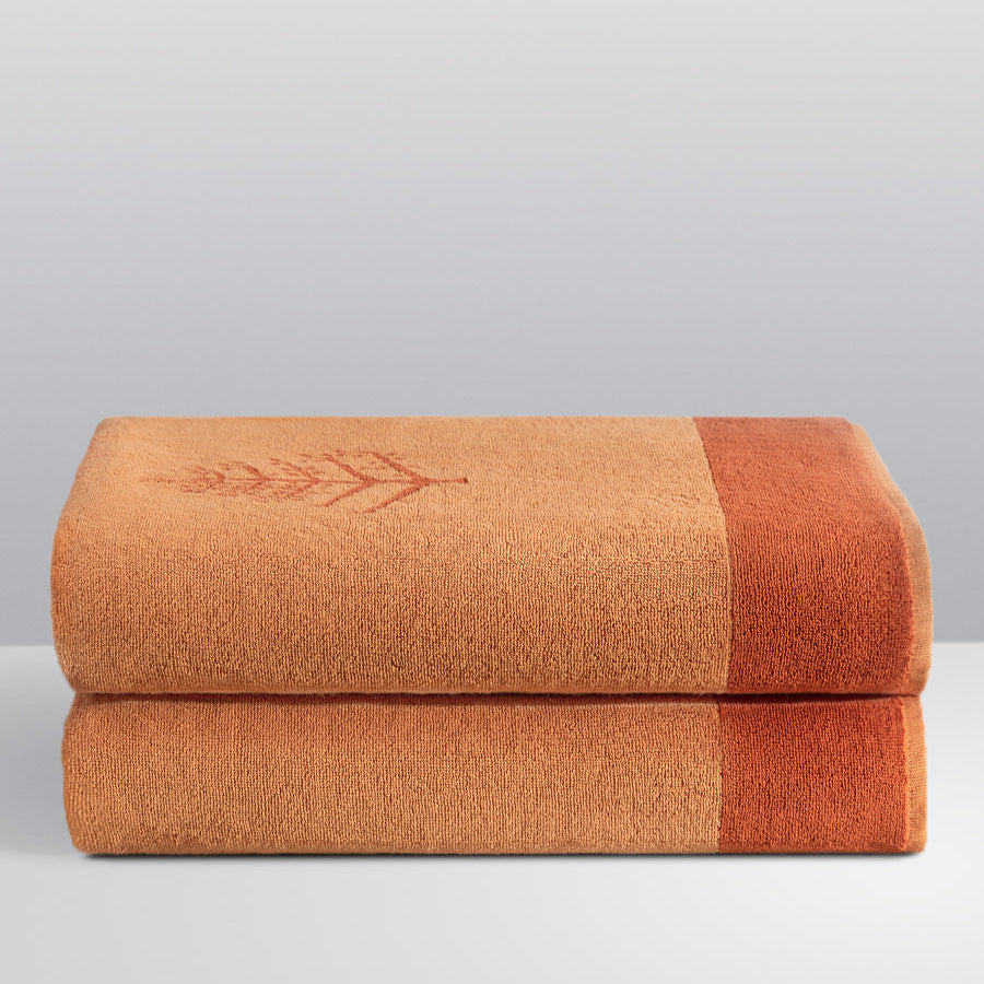 Two folded Resort Towels in an "Arabian Terracotta" color, featuring an embroidered Four Seasons logo. The towels are stacked on a white surface. - {{Arabian Terracota}}