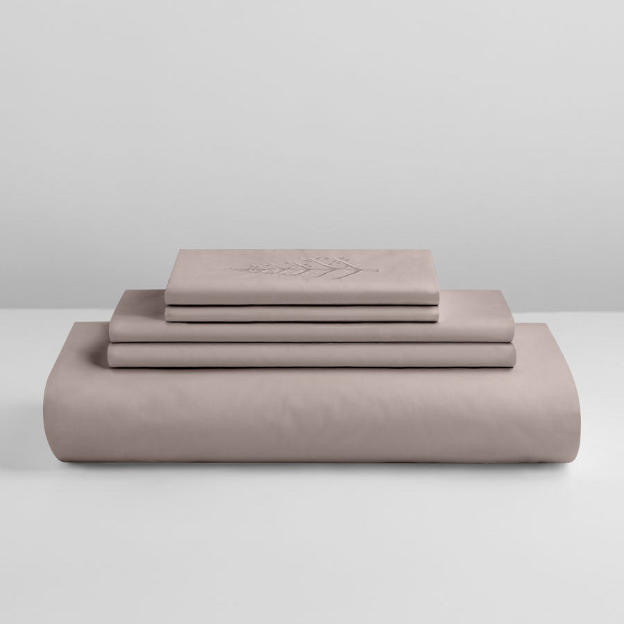 Product stack of Moroccan Sand duvet cover set—folded duvet cover, matching shams, and embroidered piece—on a white background. {{Moroccan Sand}}