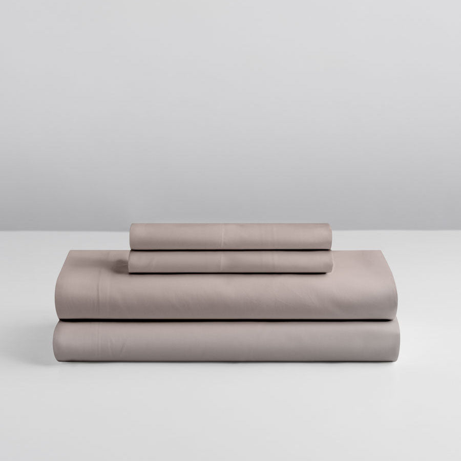 Four Seasons Signature Sheet set folded in Moroccan Sand on a grey background. {{Moroccan Sand}}