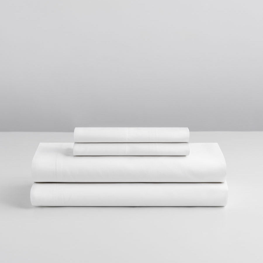 Signature White sheet set neatly stacked—deep pocket fitted sheet, flat sheet, and two pillowcases. {{Signature White}}