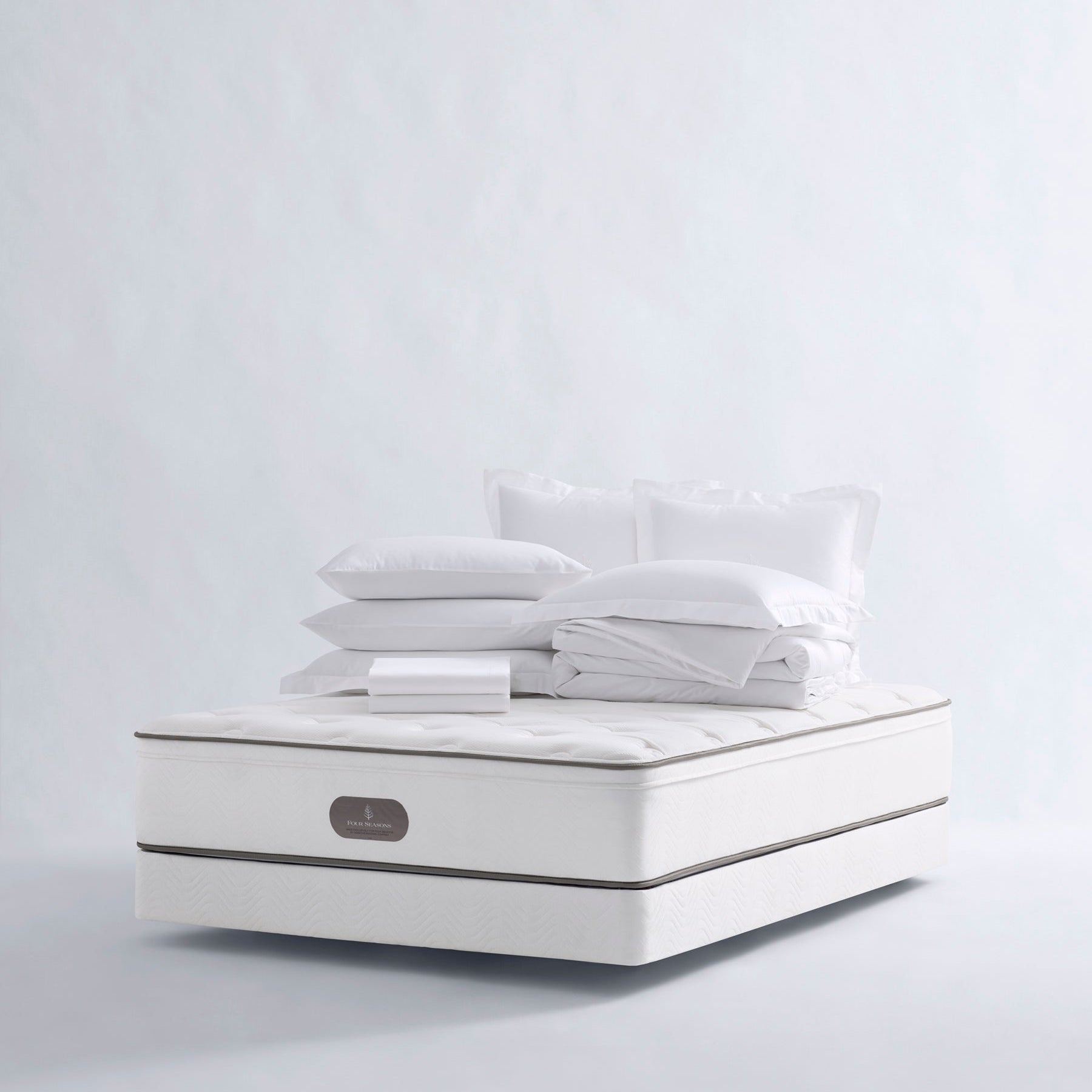 Four Seasons Bedding Set. The set includes a white mattress, a white comforter, and several white pillows, all neatly arranged on a white background.