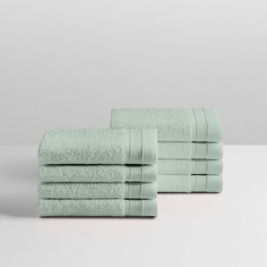 A stack of eight soft, “Florentine Sage” colored clothes neatly folded on a white surface. - {{Florentine Sage}}