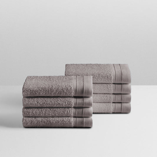 A stack of eight soft, “Hampshire Charcoal” colored bath wash clothes neatly folded on a white surface. - {{Hampshire Charcoal}}