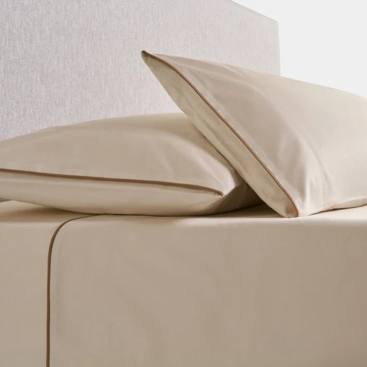 Sycamore Sheet Set in Balinese Pearl —flat and fitted sheet with modern piped hem, styled on bed with matching pillowcases. - {{Balinese Pearl}}