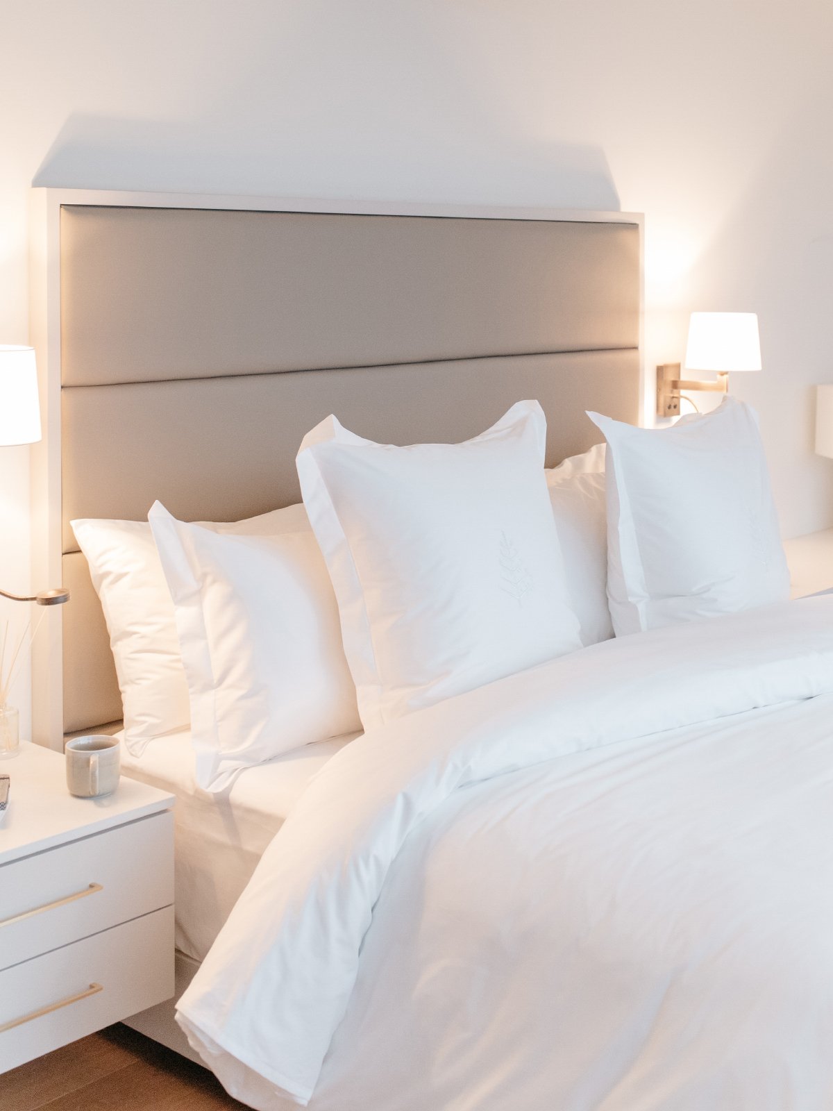 Several white pillows on a luxury hotel bed.