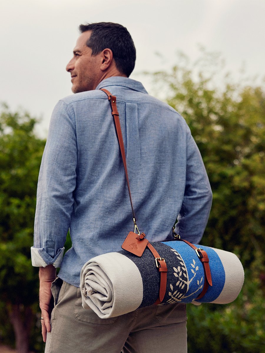 An Al Fresco Blanket rolled up with a leather travel strap and handle.