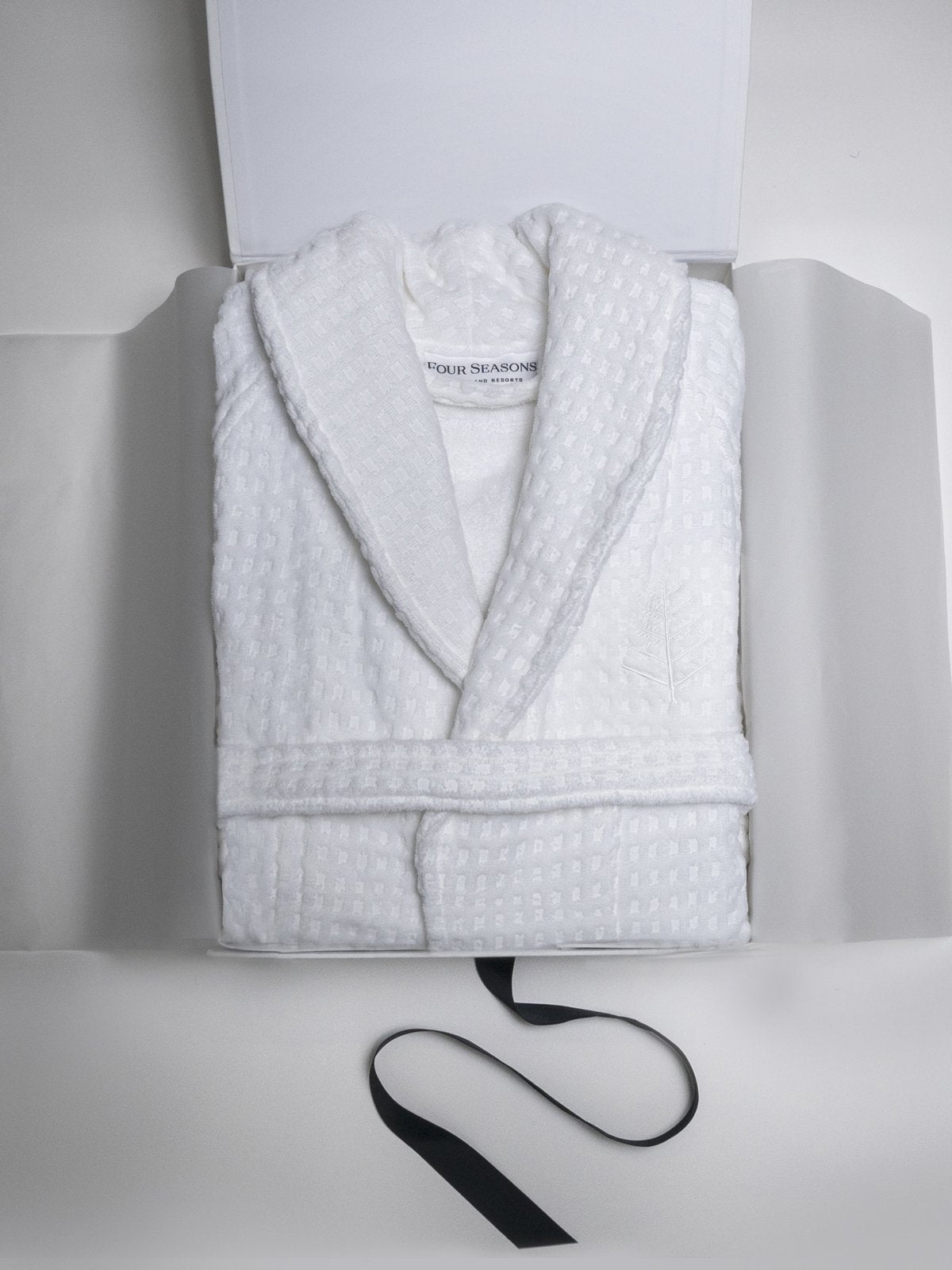 An elegant white cardboard box, open to reveal the bathrobe inside.