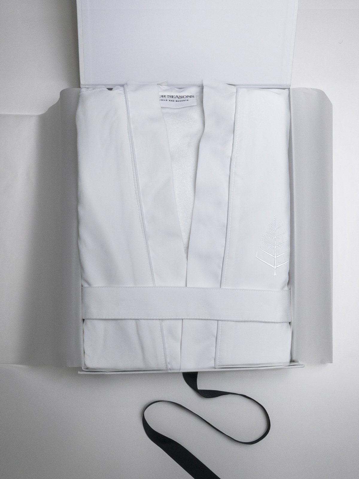 An elegant white cardboard box, open to reveal the spa robe inside.