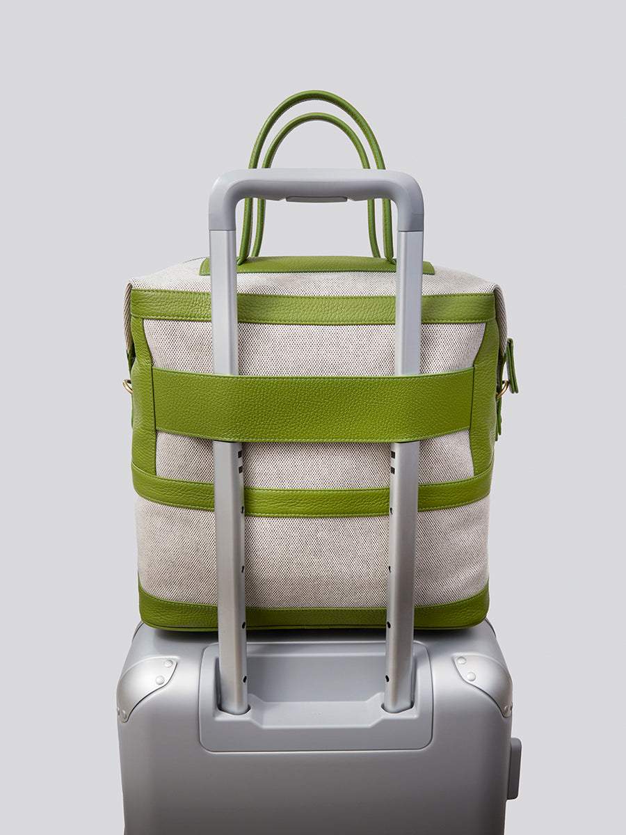 The Steamer travel bag in Kyoto Matcha from the Four Seasons Travel Collection attached to a luggage trolley.