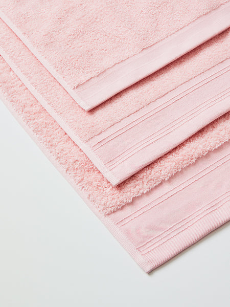 Un juego de toallas de baño de felpa beige una toalla cuelga de un  travesaño en el spa