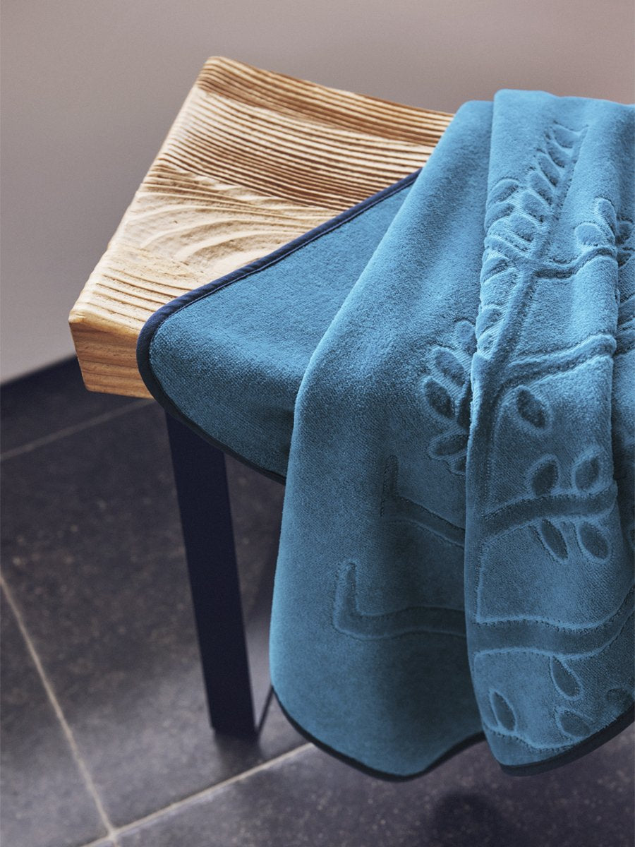An "Underwater Blue" hooded towel folded on a wooden bench in a bathroom.